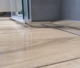 Połączenie ciemnych, strukturalnych kafli z gresem drewnopodobnym w łazience na Mokotowie.