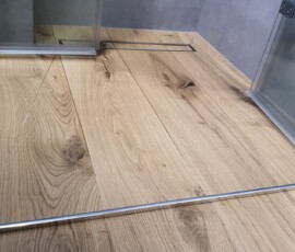 Połączenie ciemnych, strukturalnych kafli z gresem drewnopodobnym w łazience na Mokotowie.