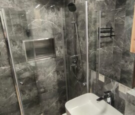 Podwieszana miska WC i nowoczesna zabudowa meblowa w jasnej łazience premium.