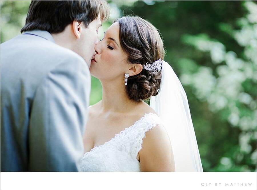 Bride and groom sharing a romantic wedding kiss in a garden setting.