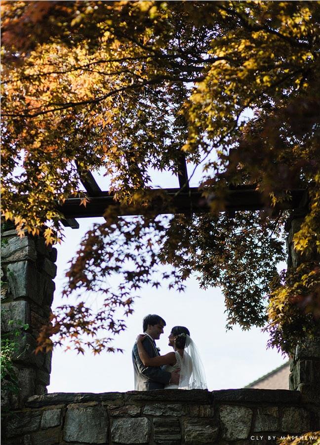 Bride and groom framed by stone archway at Le Chateau garden wedding venue