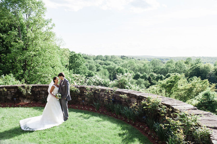 Bride and groom sharing a romantic moment with panoramic garden views in the background.