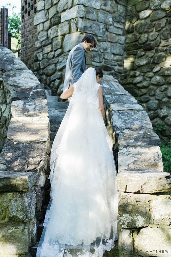 Bride and groom walking on historic stone staircase at Le Chateau wedding venue grounds