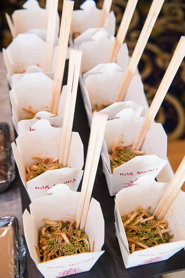 Asian noodle boxes with chopsticks served at a banquet catering station.