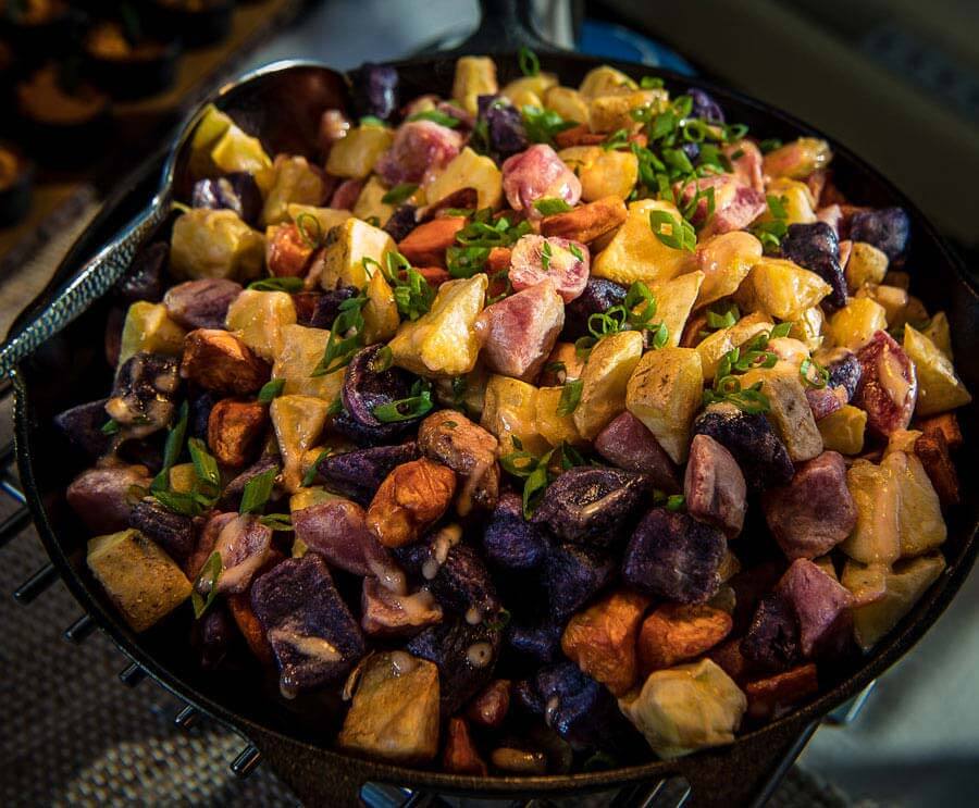 Loaded spud bar with colorful roasted potatoes and gourmet banquet toppings.
