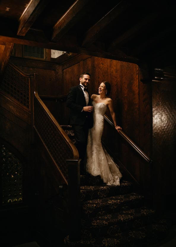 Bride and groom posing on grand staircase inside Le Chateau wedding venue
