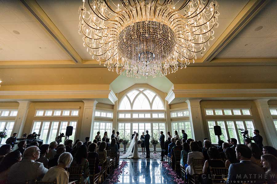 Elegant indoor wedding ceremony beneath a grand chandelier at Le Chateau Banquets ballroom