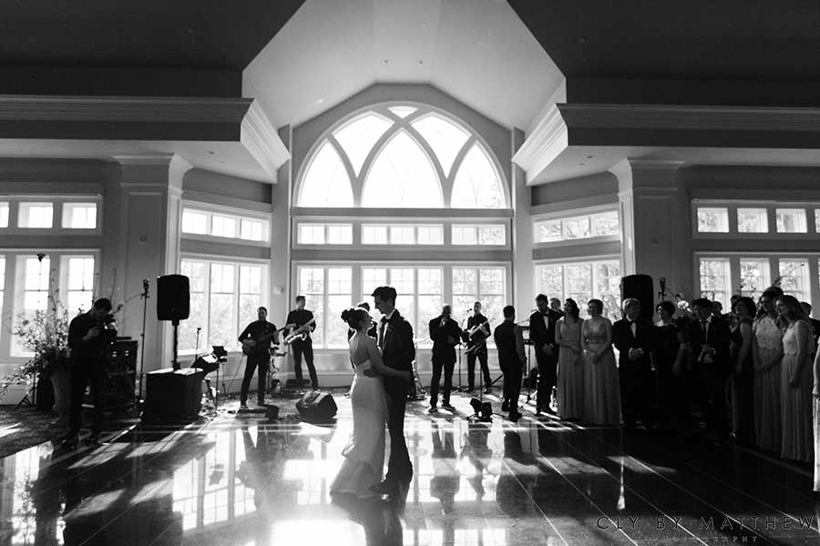 Bride and groom sharing their first dance in a grand ballroom with live music.