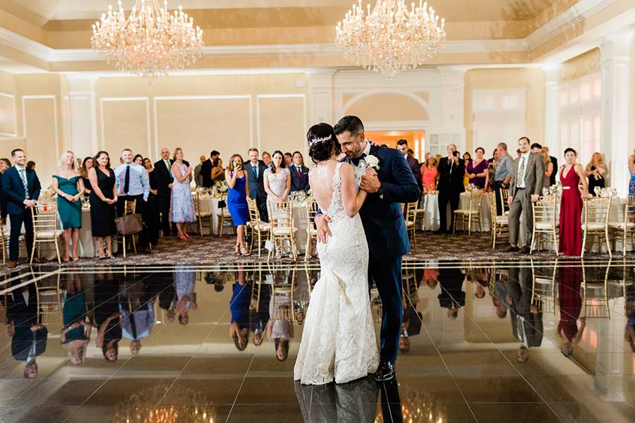 Bride and groom sharing their first dance in an elegant ballroom reception.