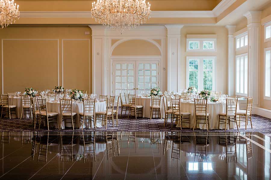 Elegant ballroom reception space with crystal chandeliers and beautifully set dining tables.