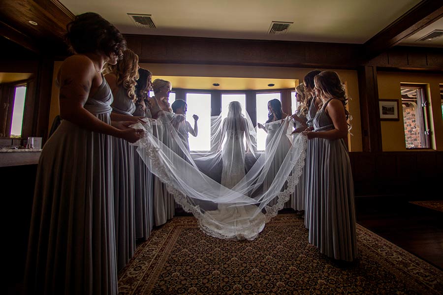 Bridesmaids holding bride’s veil in elegant bridal suite at Le Chateau Banquets