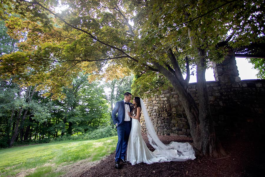 Bride and groom beneath trees on Le Chateau grounds during outdoor wedding portrait session