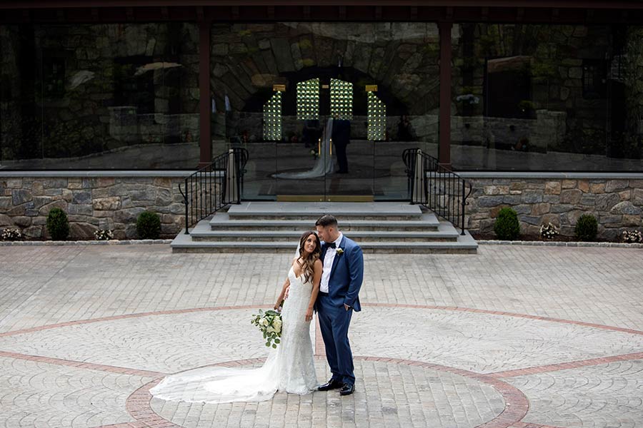 Bride and groom posing in front of Le Chateau Banquets entrance before their wedding reception