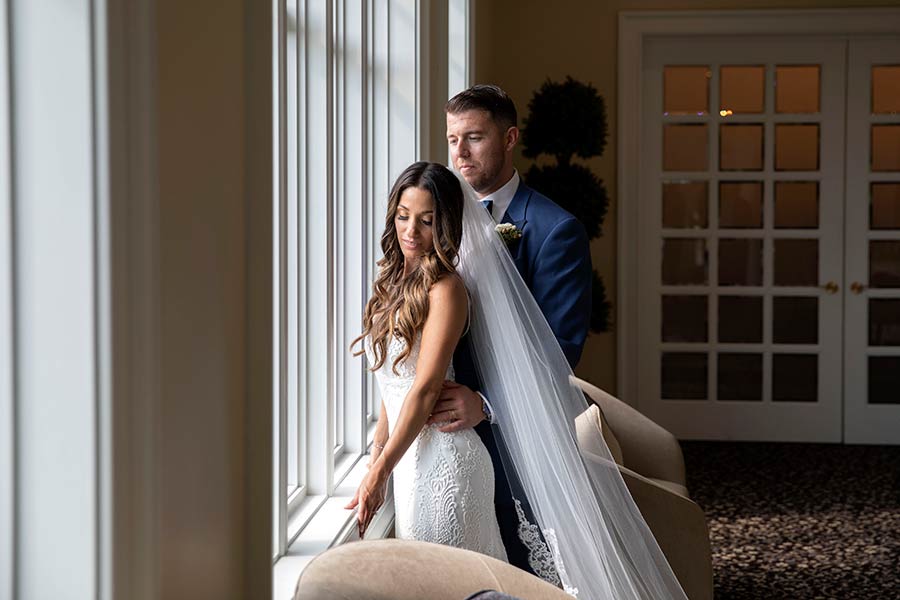 Bride and groom sharing a quiet moment by the venue's elegant window seating.
