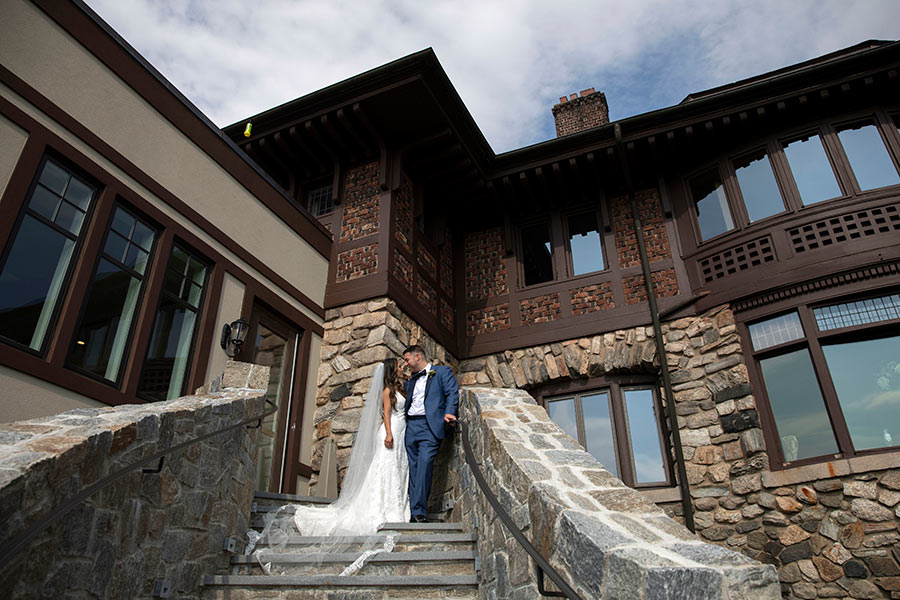 Bride and groom on stone staircase outside an elegant estate wedding venue.