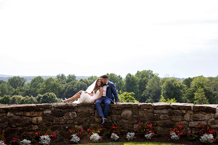 Bride and groom sharing a romantic moment on stone overlook at Le Chateau wedding venue grounds