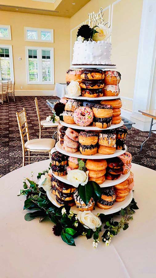 Wedding donut tower display with floral accents for a unique dessert station.