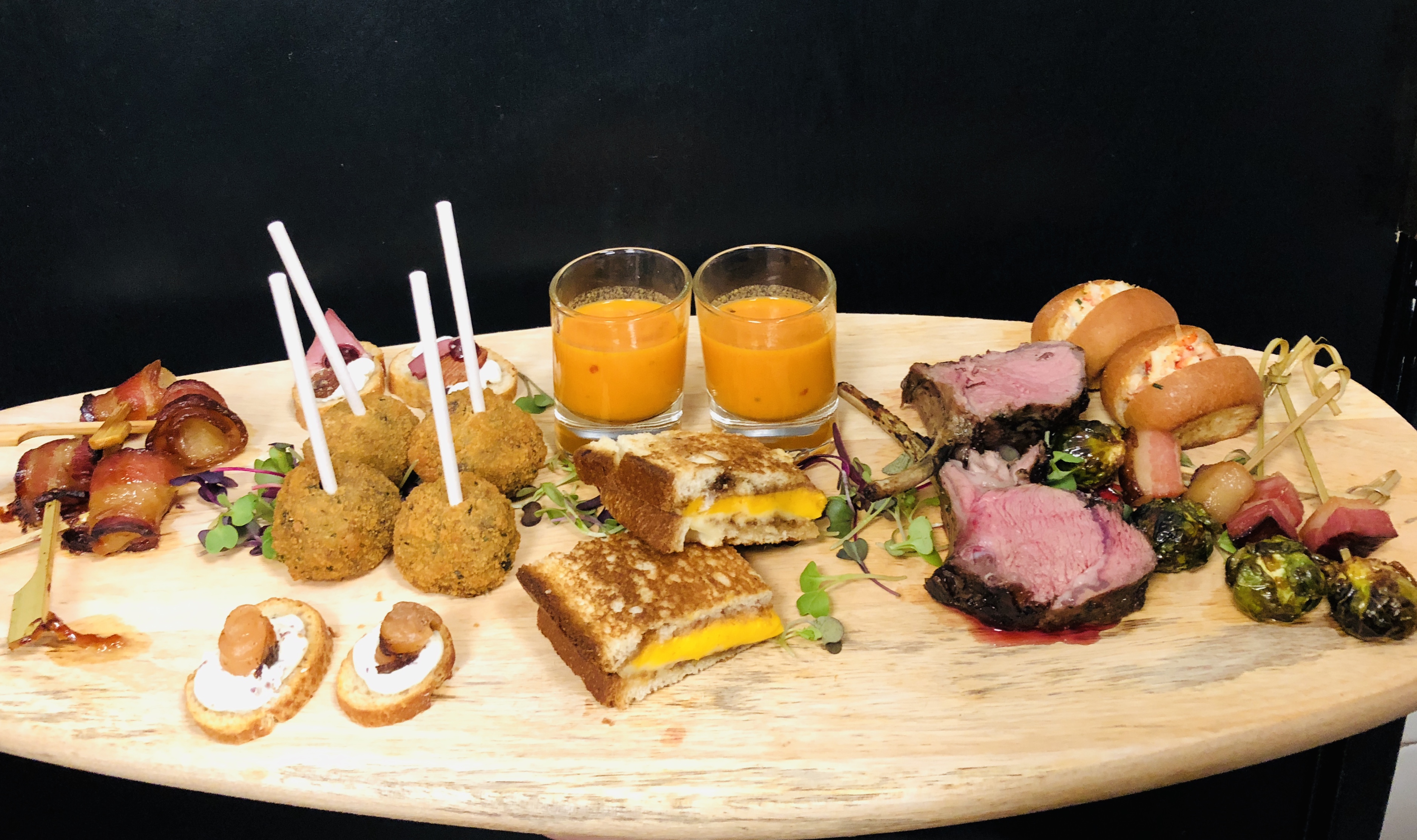 Assorted gourmet hors d’oeuvres displayed on a banquet catering presentation board.