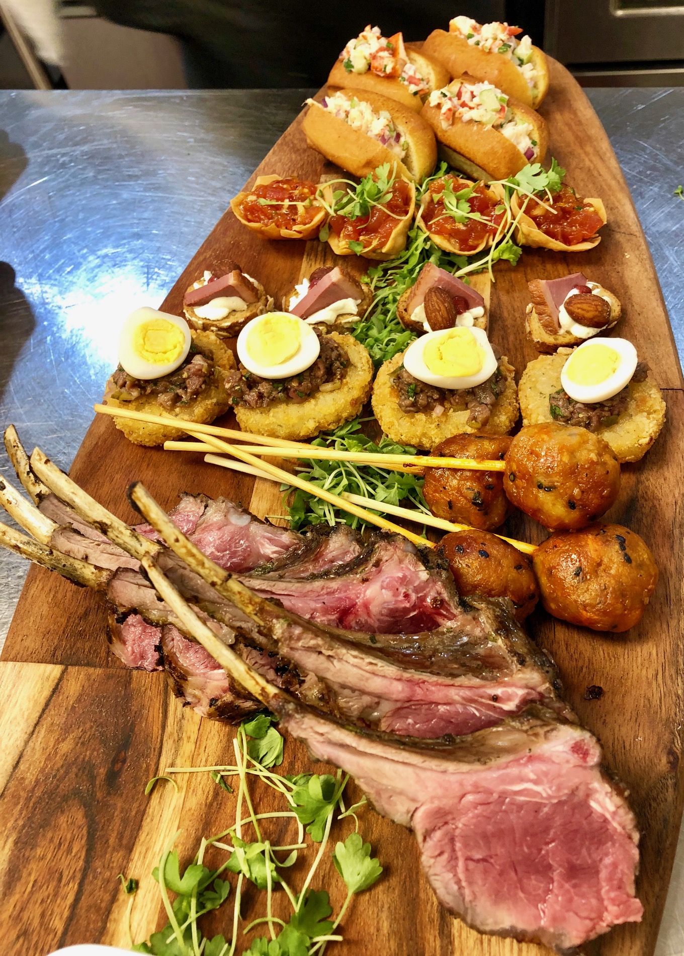 Assorted gourmet hors d’oeuvres featuring lamb chops, sliders, and elegant cocktail bites.