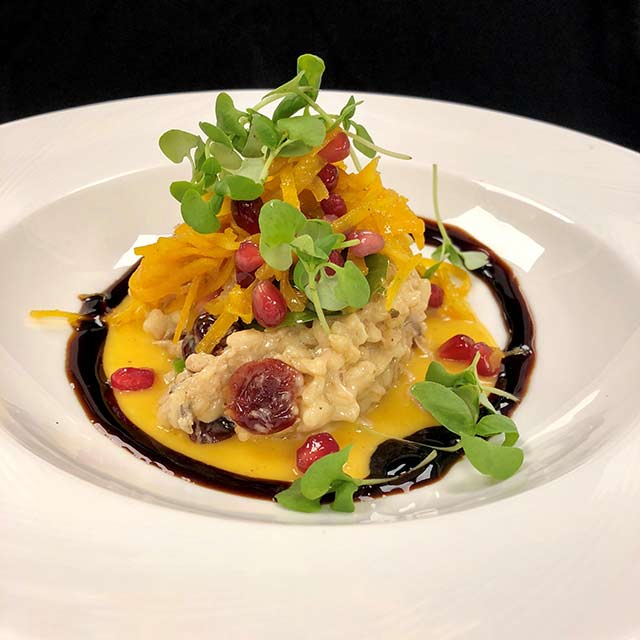 Hudson Valley duck confit risotto with citrus, pomegranate, and microgreens.