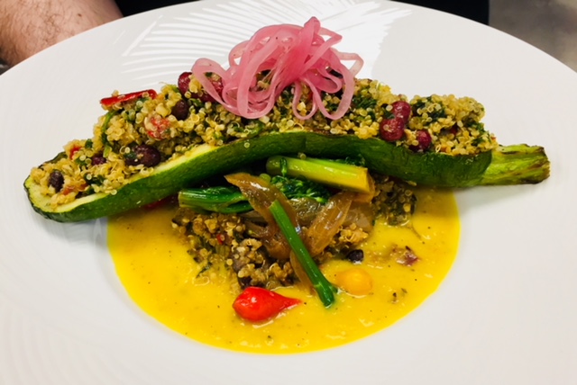 Quinoa stuffed squash entrée with vibrant vegetables and gourmet banquet presentation.