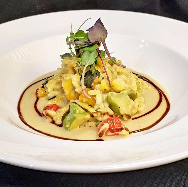 Summer squash and corn risotto with fresh vegetables in a creamy gourmet sauce