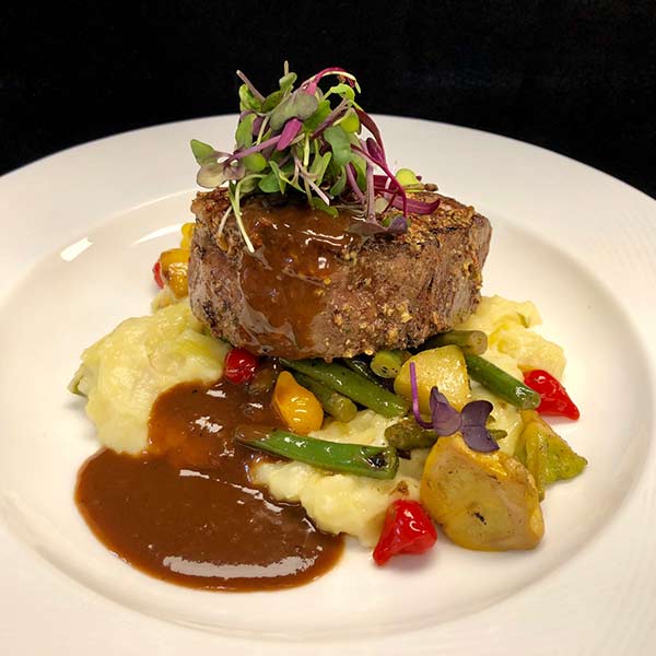 Whole grain mustard beef tenderloin with mashed potatoes, vegetables, and demi-glace.