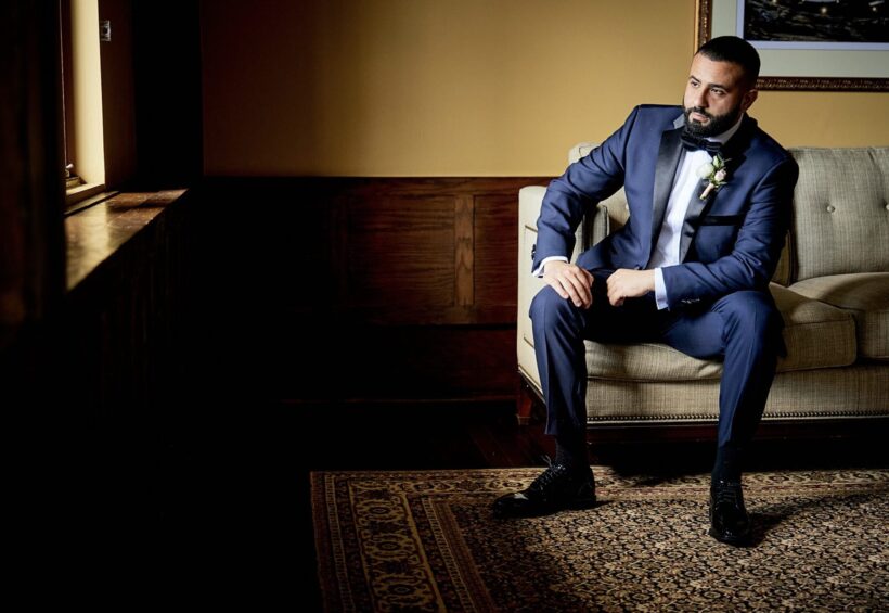Groom relaxing in stylish wedding suite before ceremony at Le Chateau Banquets