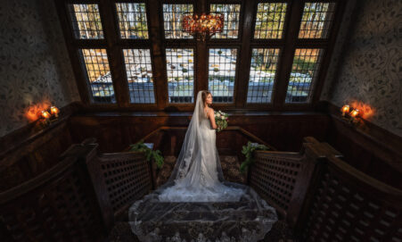 Bride standing on elegant staircase in Le Chateau wedding venue interior