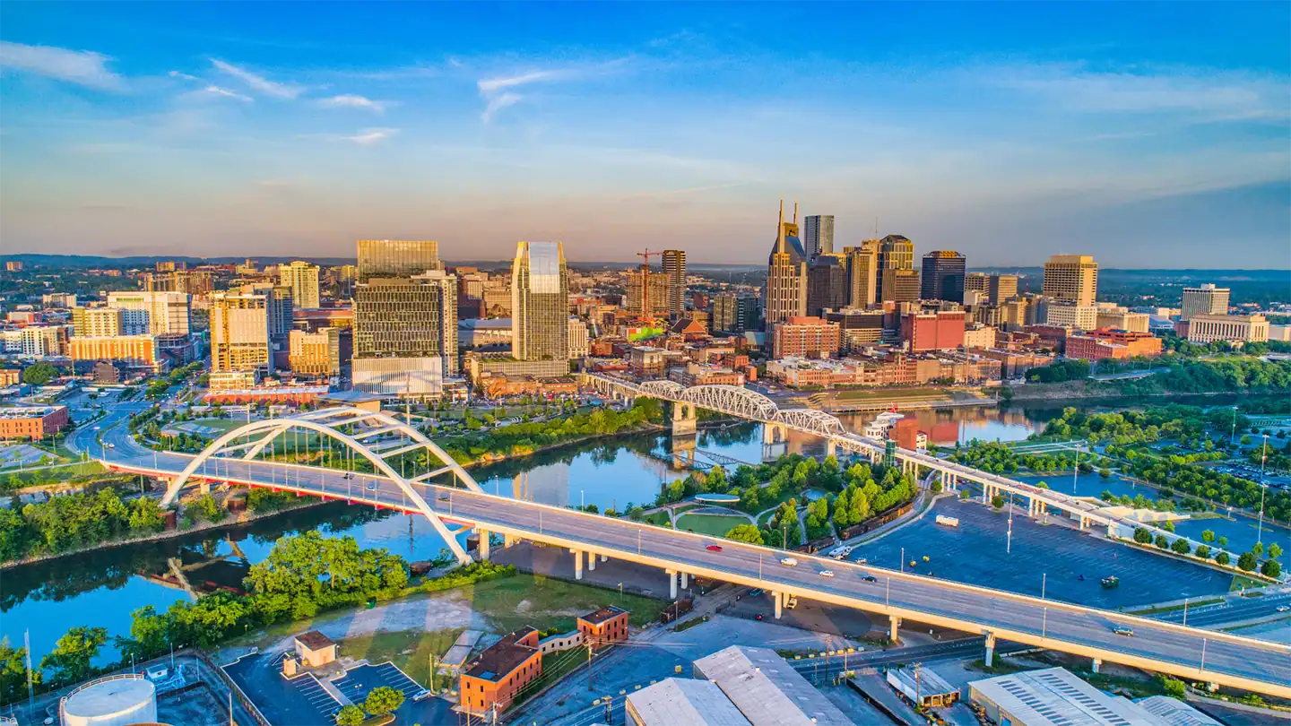 Aerial view of a city skyline with a river, bridges, and modern buildings under a blue sky.