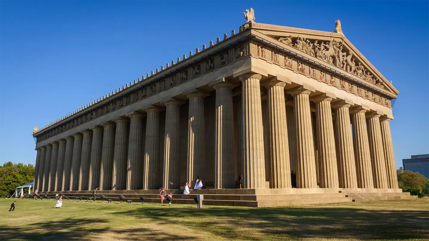 The Parthenon, an ancient Greek temple on the Acropolis in Athens, with tall columns and detailed pediment, under a clear blue sky.