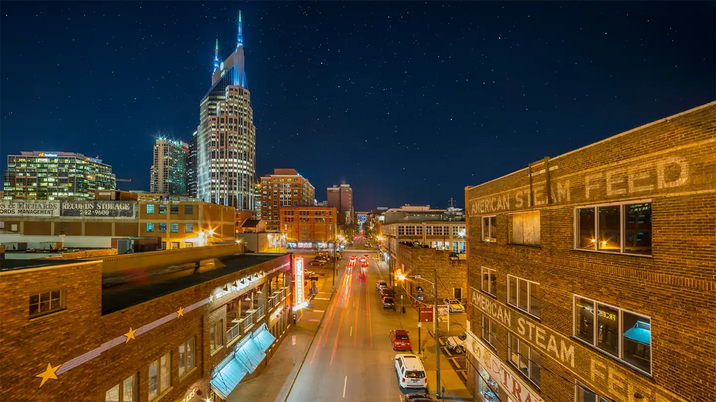 Night view of Nashville downtown with the AT&T Building, known as the 'Batman Building', illuminated against a starry sky.