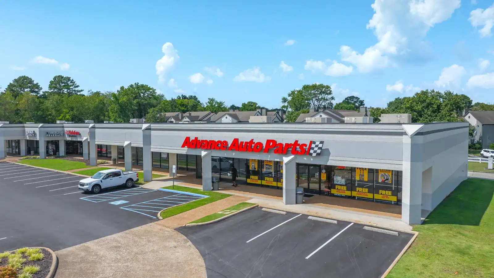 Exterior view of Advance Auto Parts store with parking lot and clear sky.