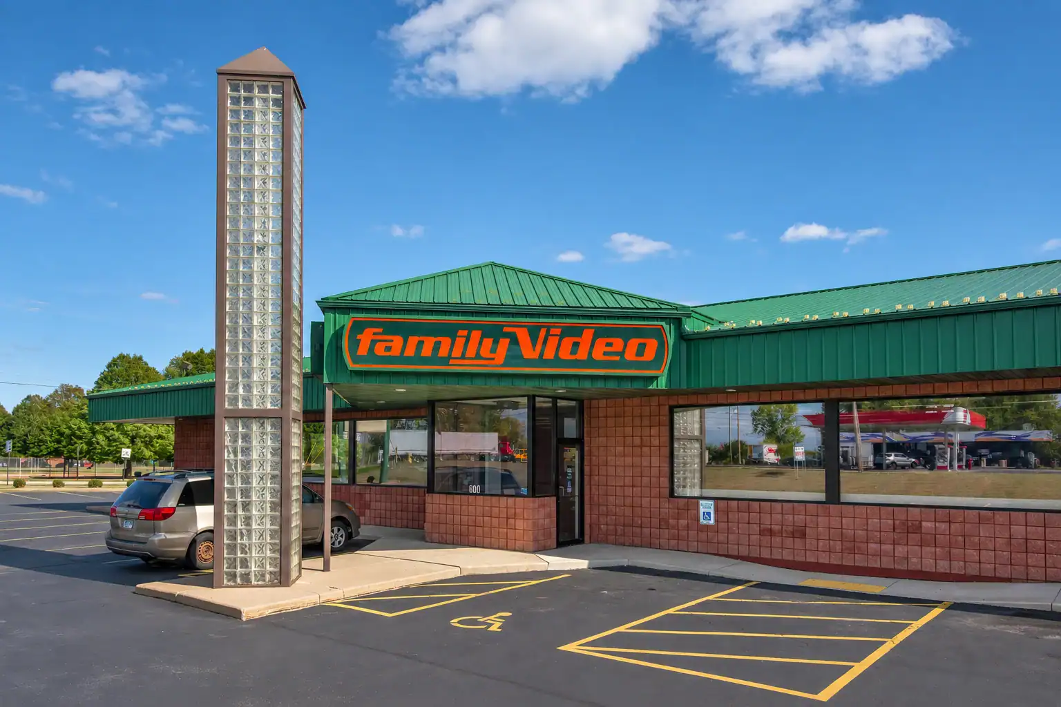Family Video store with a green roof, brick walls, and a parking lot with handicapped and regular parking spaces.