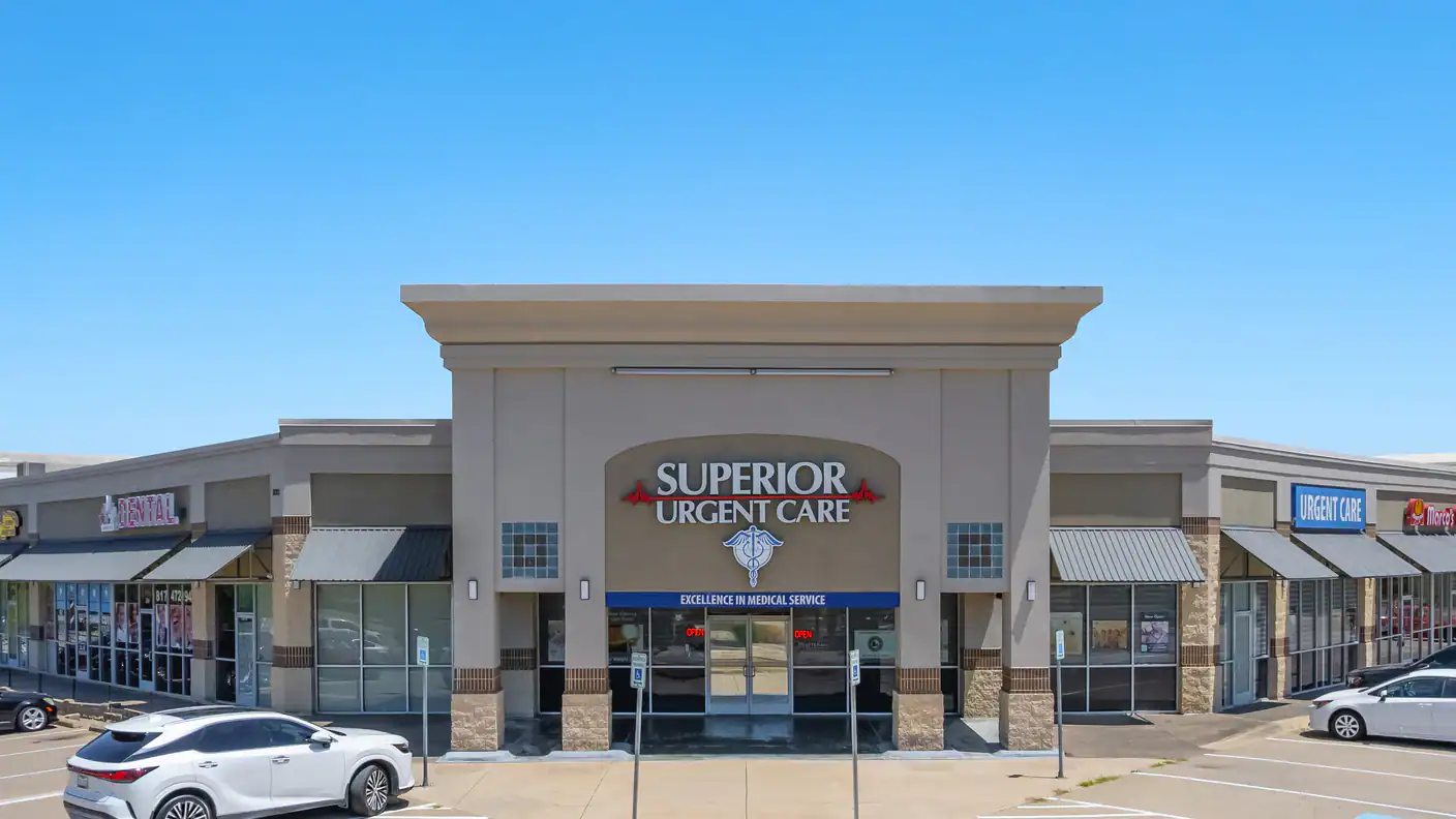 Exterior view of Superior Urgent Care clinic with signage and parking lot in front under clear blue sky.