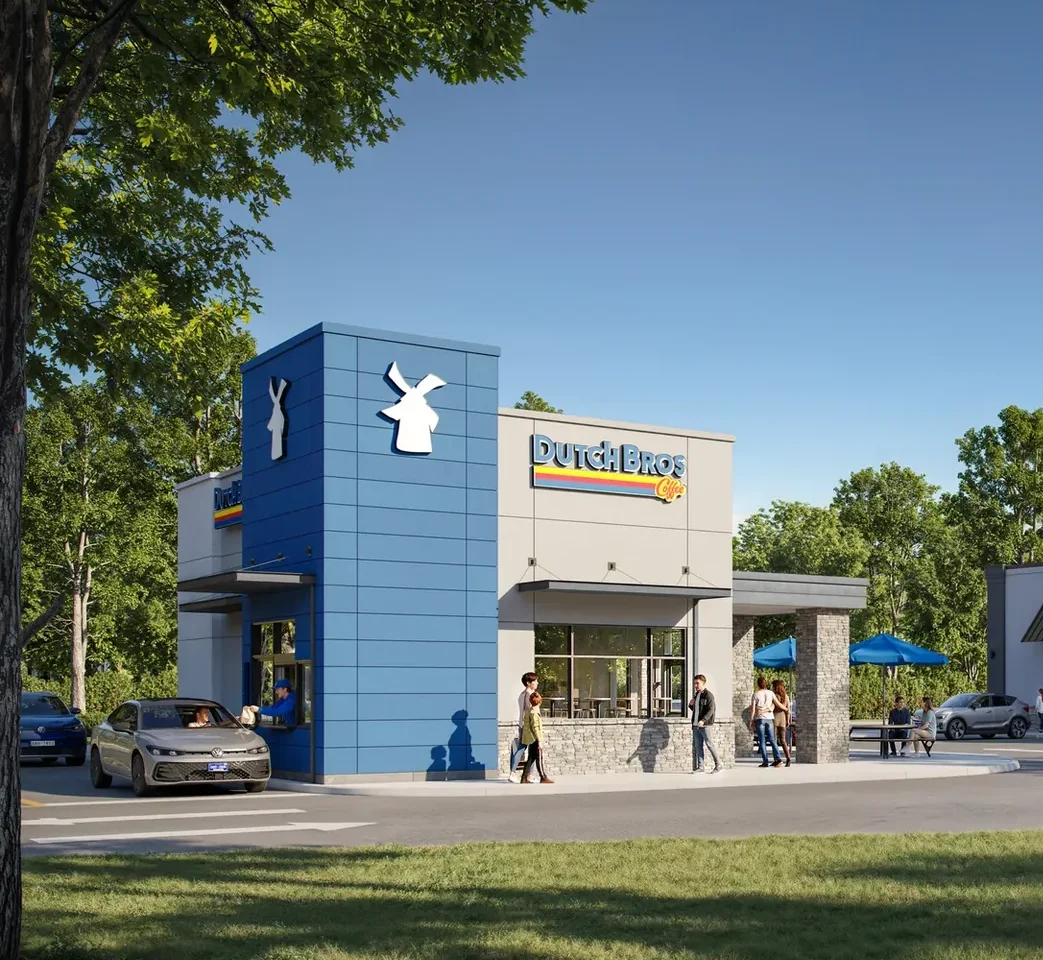 Exterior view of a shopping center with multiple stores, parking lot, and people walking outside on a sunny day.