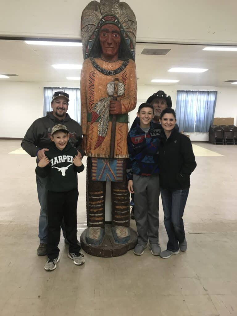Native American-style wooden statue with family members.