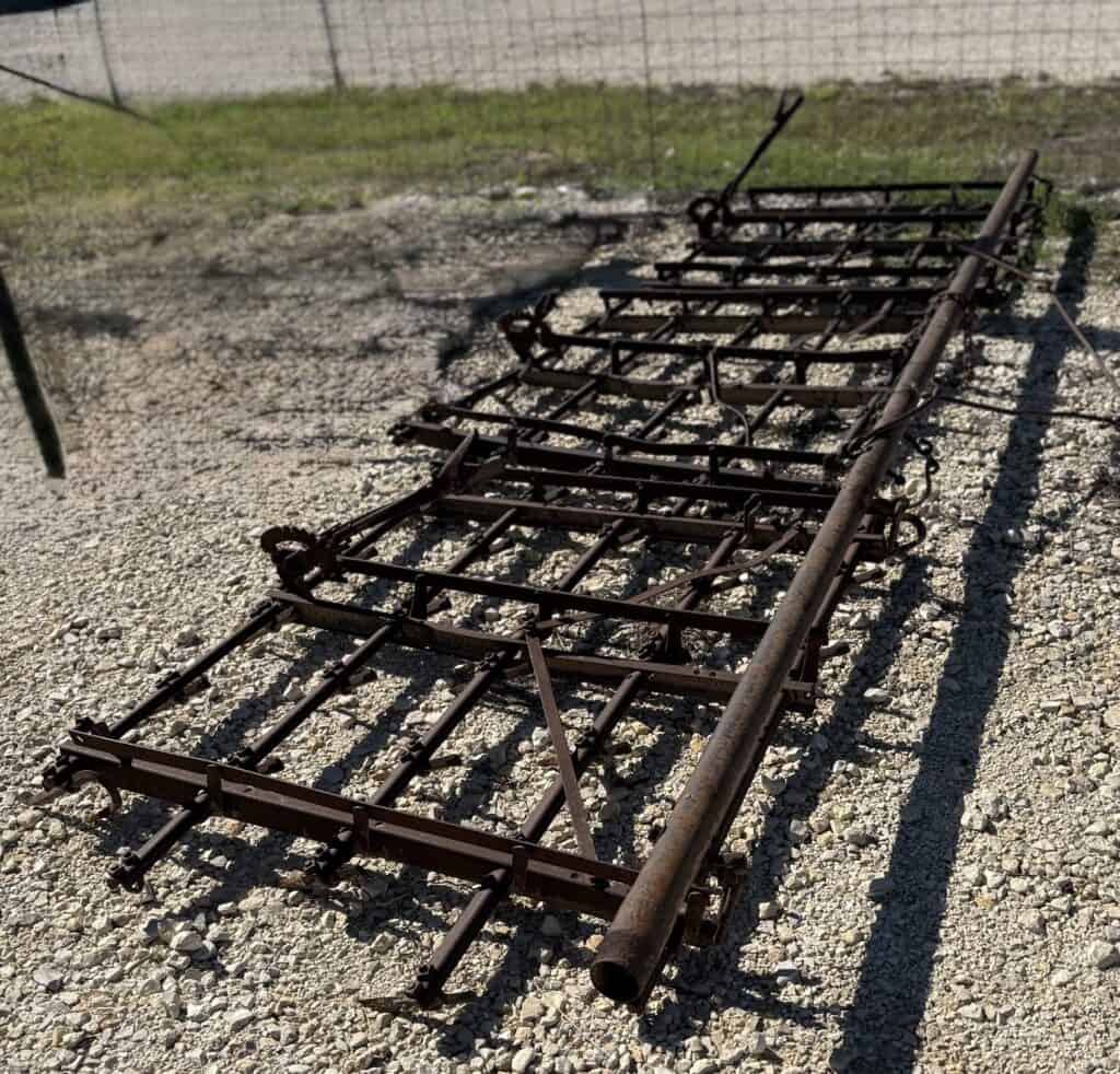 Rusty metal ladder on gravel ground, ideal for outdoor auction or salvage projects.