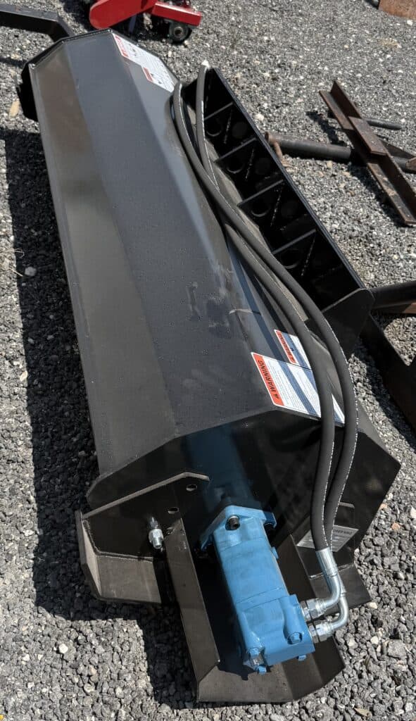 Hydraulic industrial attachment with hoses and motor for heavy machinery.