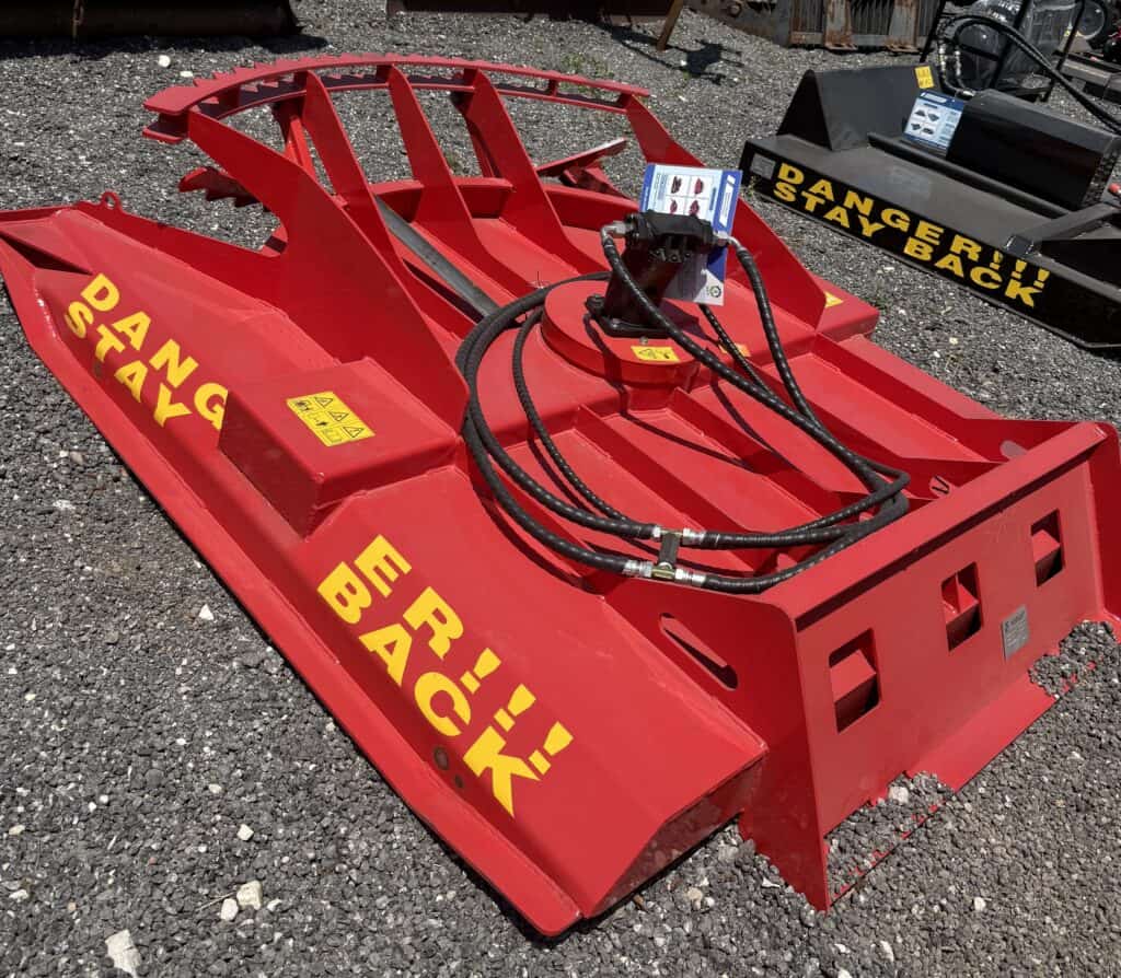 Rotary cutter attachment for farm machinery, bright red with yellow "DANGEROUS STAY BACK" warning la.