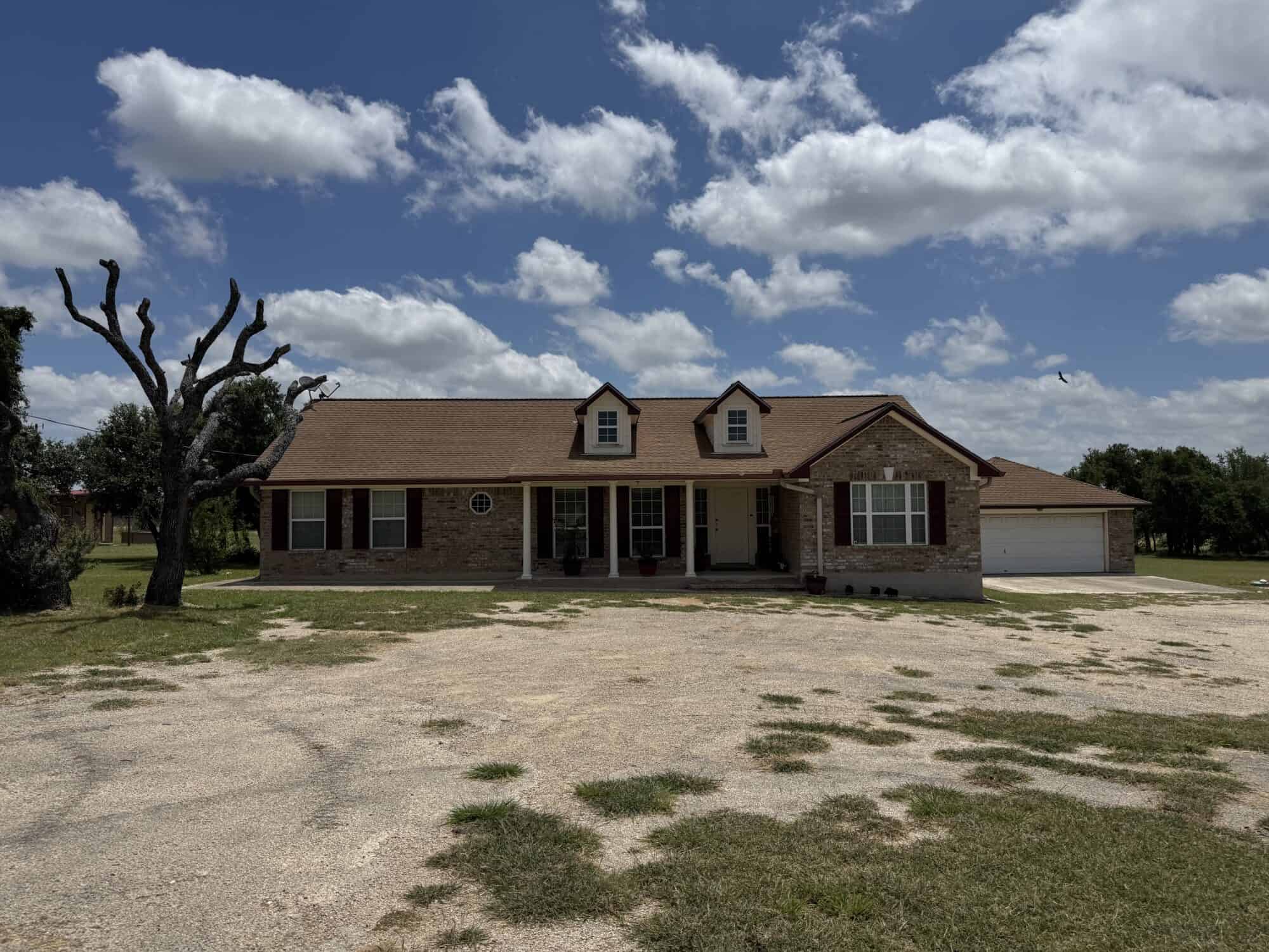 Spacious ranch-style house with front porch and garage under a blue sky.