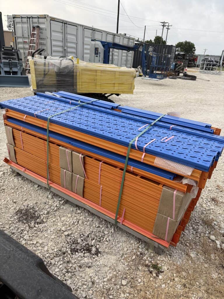Stacked construction scaffolding and safety barriers at auction site.