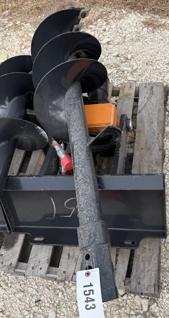 Large black auger attachment for construction or farming equipment.