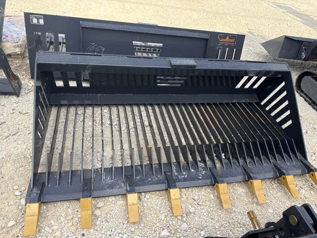 Black grader bucket with yellow teeth for heavy machinery.