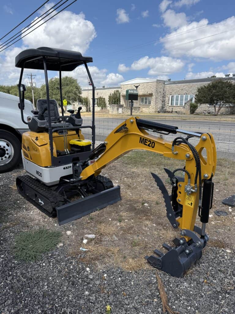 Yellow mini excavator with black arm and bucket at auction site.