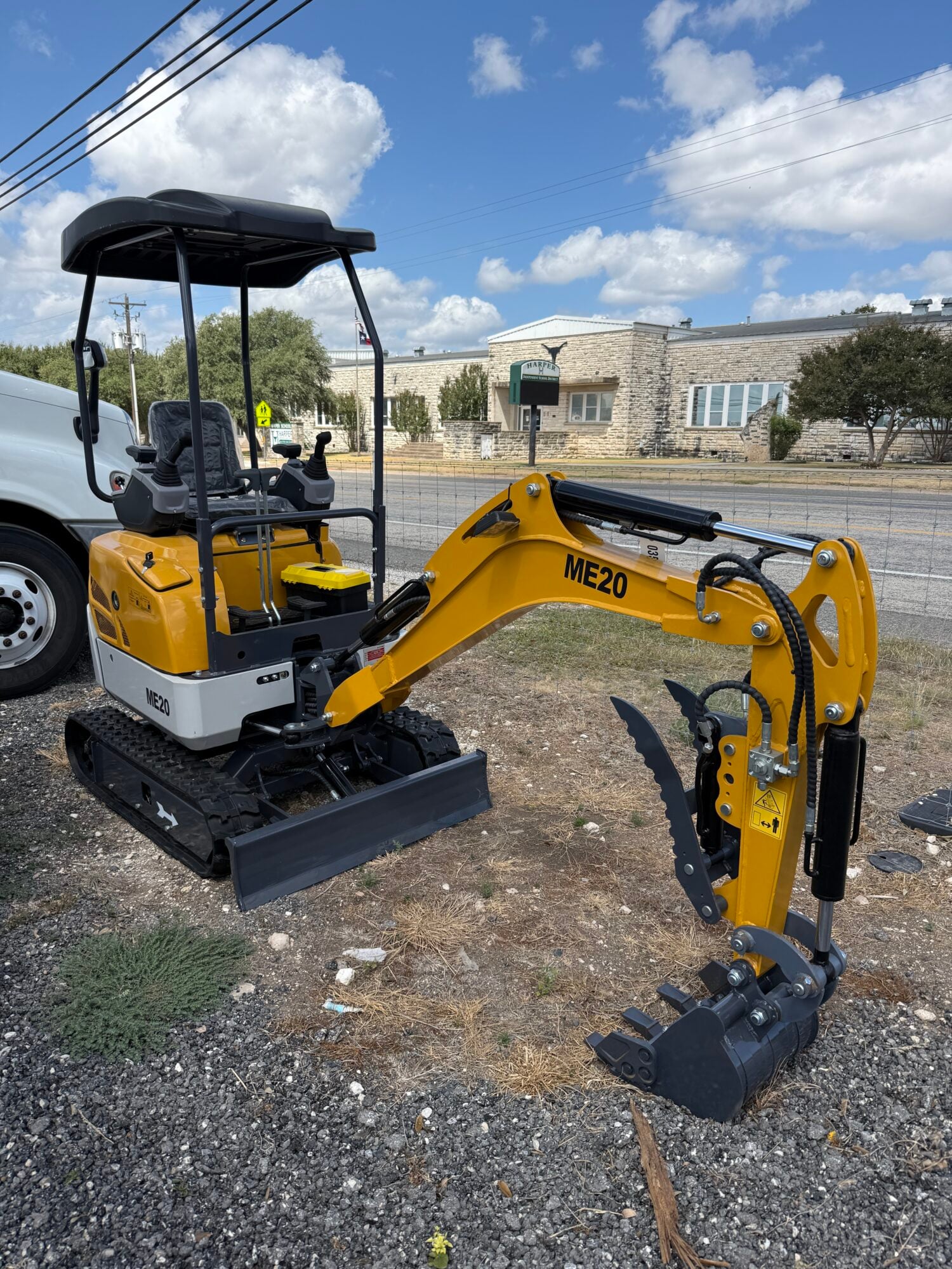 Yellow mini excavator with black arm and bucket at auction site.