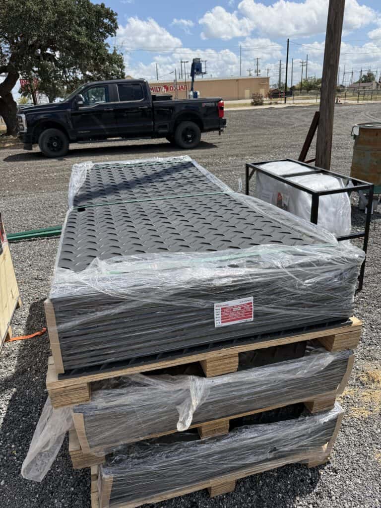 Stacked metal grates on pallets at an auction site.