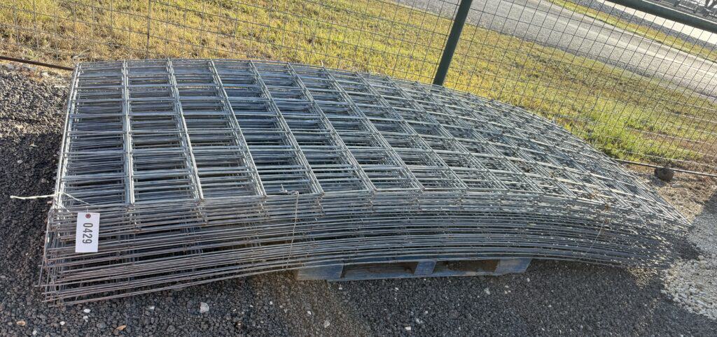 Metal fencing panels stacked outdoors at Garrett Realty & Auction.
