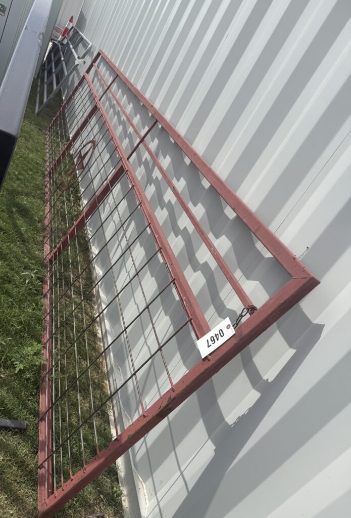 Red metal gate with wire mesh, outdoor setting, for auction.
