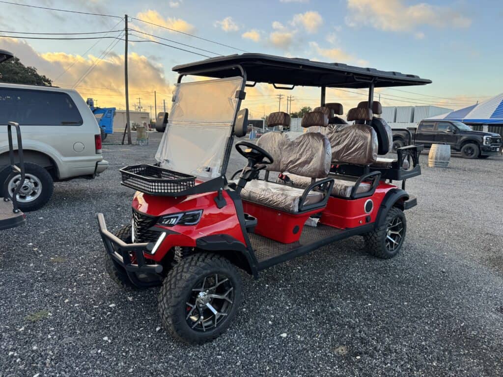 Red golf cart with four seats and canopy at auction site.